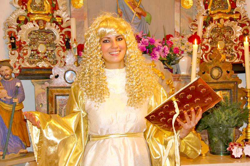 Das Christkind breitet die Arme in der Kapelle aus, mit einem Buch in der Hand.