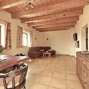 Wohnbereich mit Holzdecke, Essecke und Couch mit Durchreiche zur Kueche