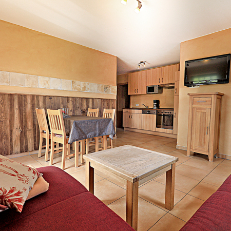 Ferienwohnung mit einer Holzdekowand, einer Essekce und einer Couch, sowie eine Kueche und SAT/TV