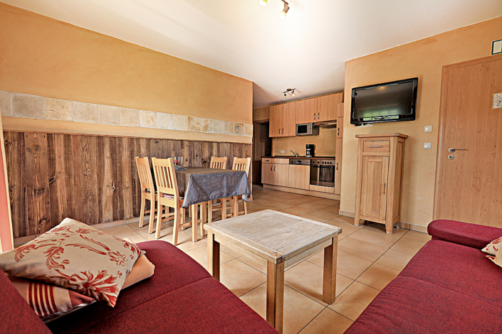 Ferienwohnung mit einer Holzdekowand, einer Essekce und einer Couch, sowie eine Kueche und SAT/TV