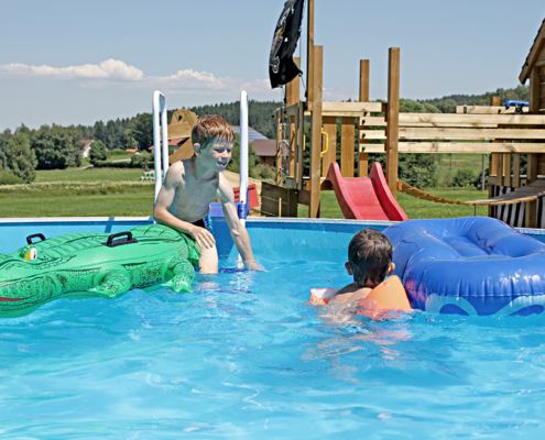 Zwei Kinder spielen auf der Luftmatraze im Pool von Paulas Bauernhof