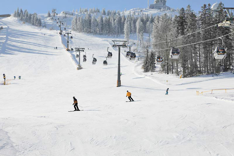 Skihang mit Kabinenlift mit verschneiten Bäumen, sowie einigen Skifahren