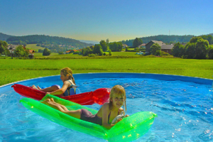Inmitten schöner Landschaft spielen zwei Kinder auf der Luftmatraze im Pool