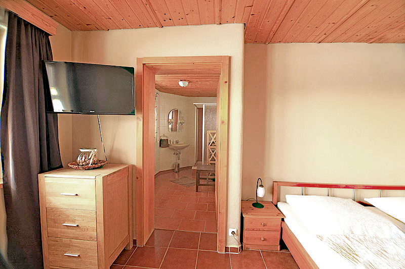 Apartment mit Bett, TV, Sideboard und Türe zum Badezimmer