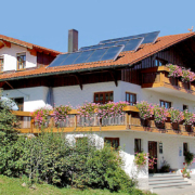 Ferienhaus mit großen Balkon, darauf viele Geranien und Sträucher um das Haus