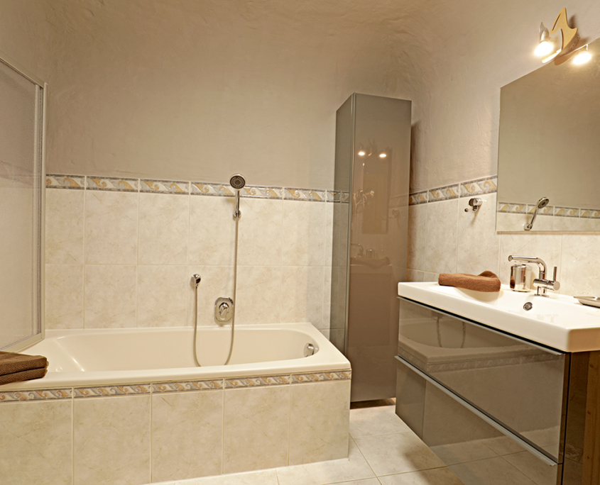 Badezimmer mit Badewanne Duschkabine und Badmöbel, Waschbecken mit Spiegel und Handtücher