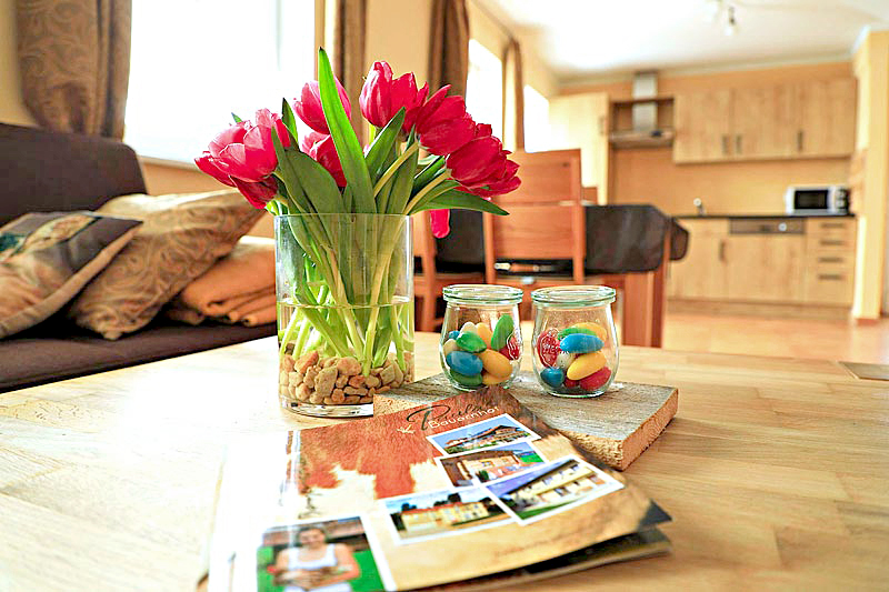 Rote Tulpen, Ostereier und Hausprospekt auf den Tisch, dahinter eine Küche und eine Couch
